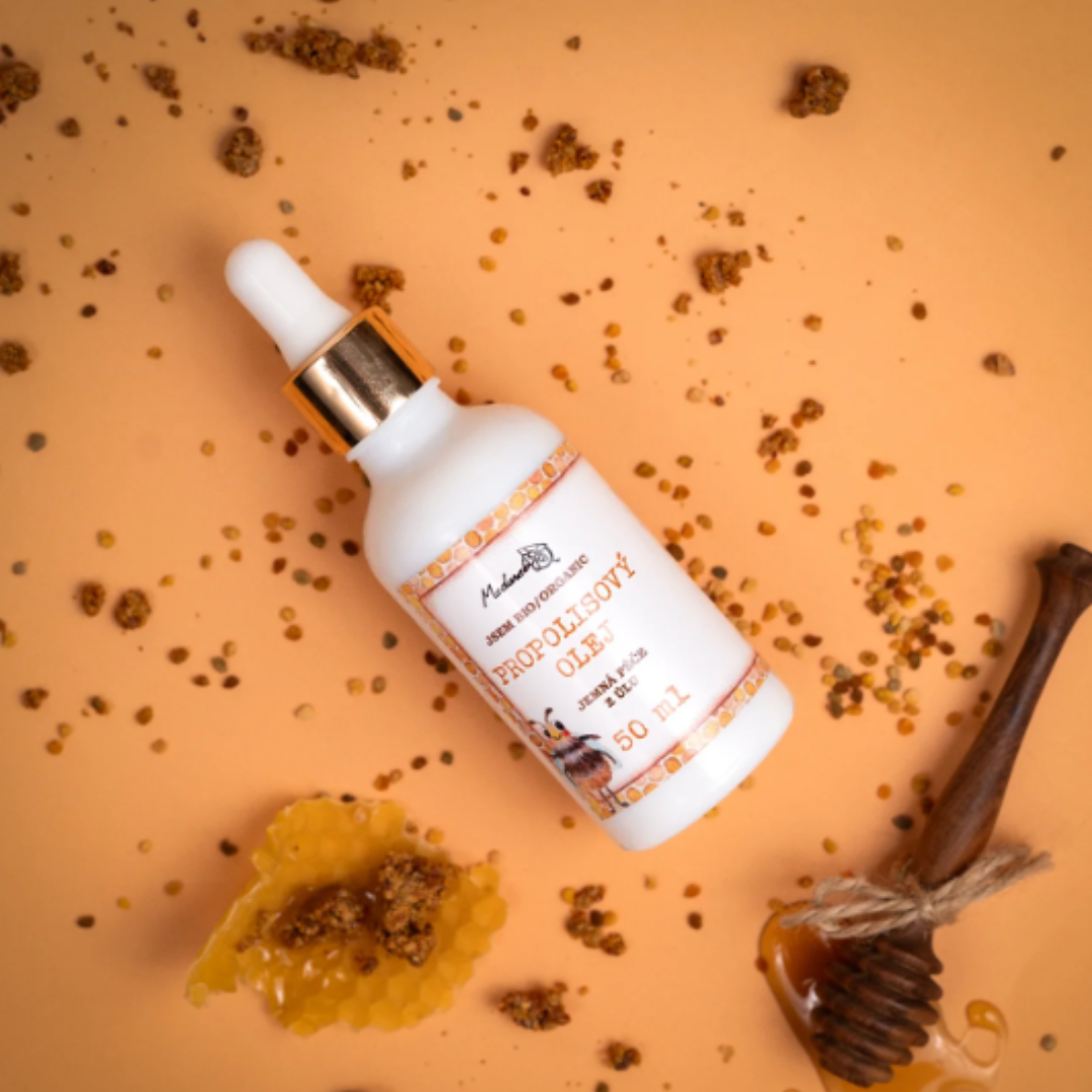 Medarek Propolis Oil dropper bottle on an orange background with scattered propolis granules, honeycomb, and a wooden honey dipper.